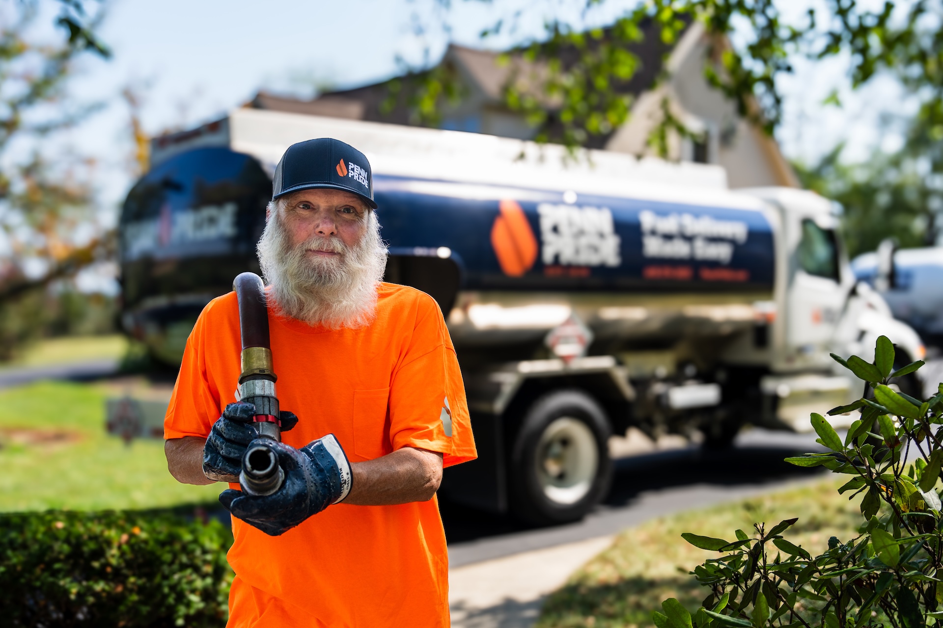 Penn Pride worker carrying a fuel hose away from a Penn Pride truck.