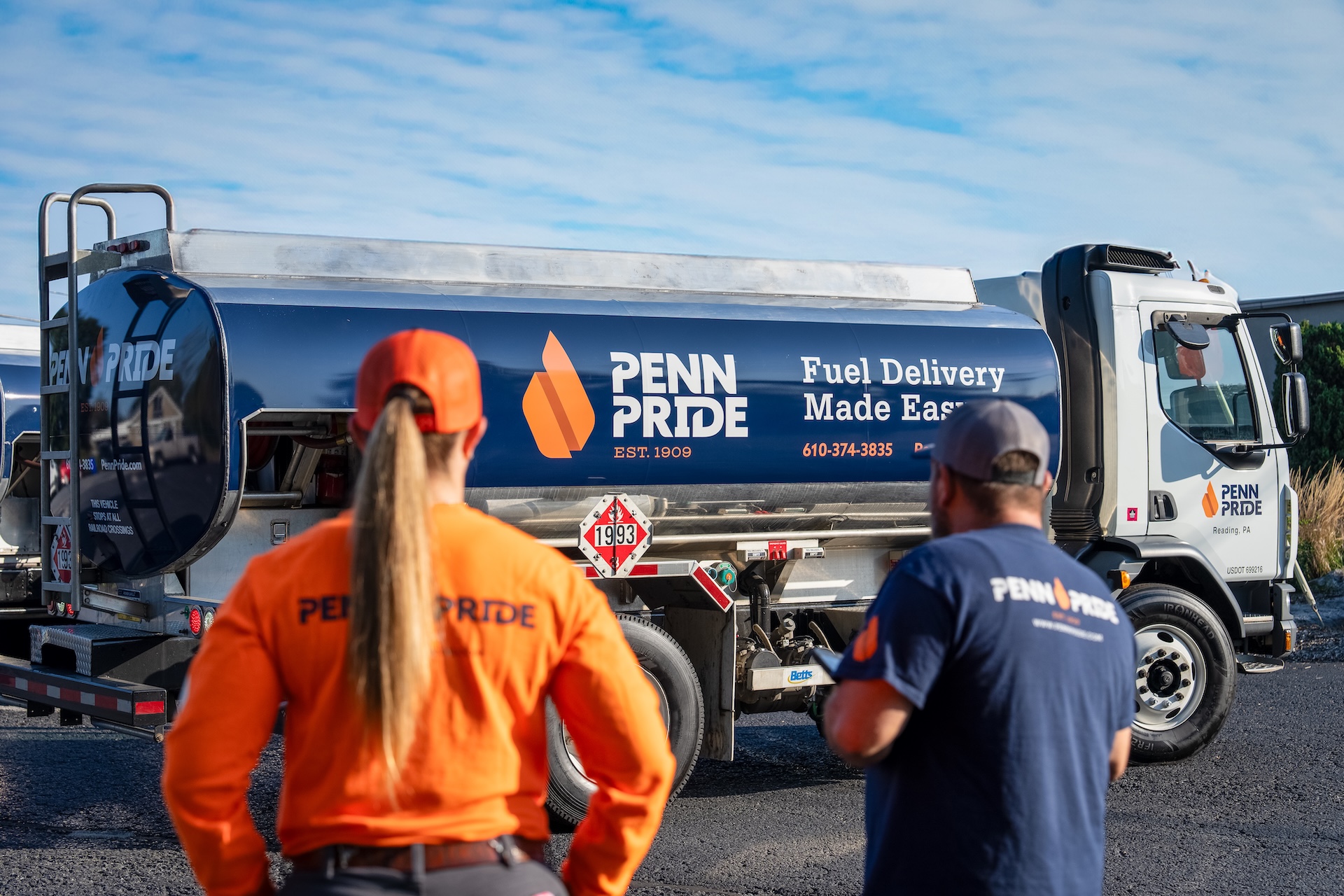 Two Penn Pride workers standing with their backs turned to the camera in front of a Penn Pride truck.