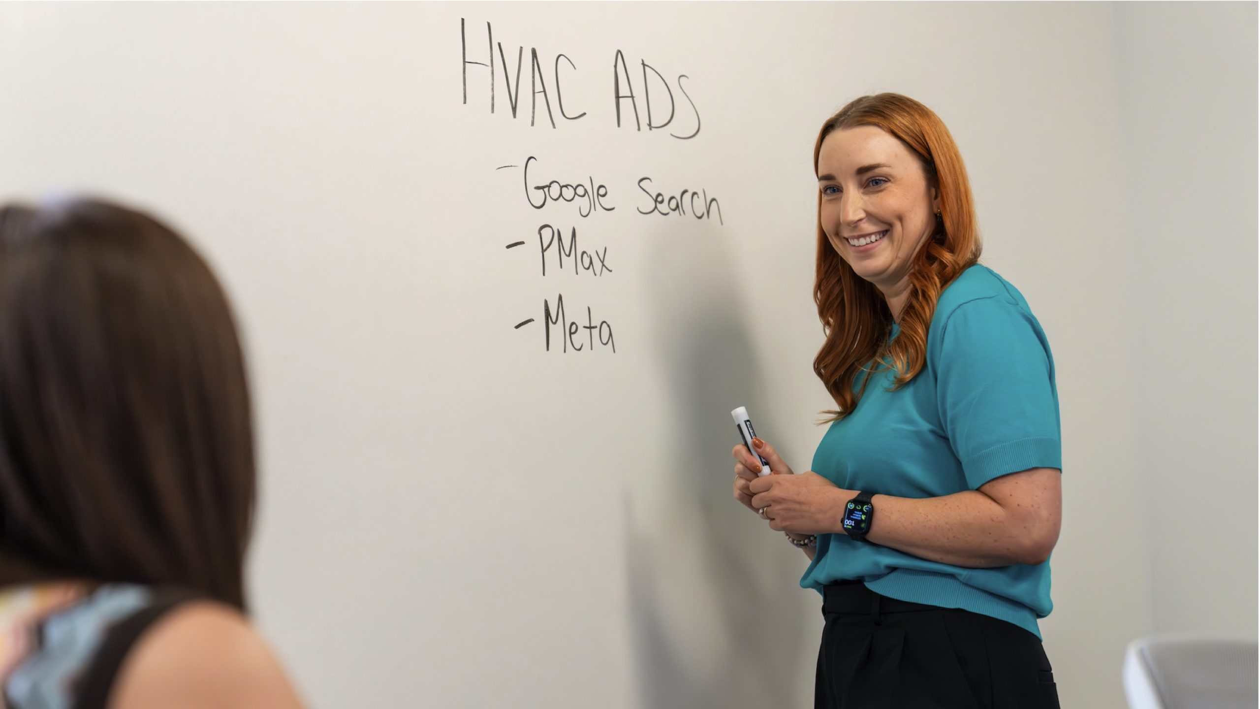 Woman writes on dry erase wall about energy marketing strategies.