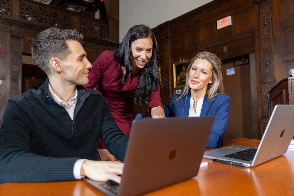 FELTG-250 Three people in professional attire looking at a laptop on a table