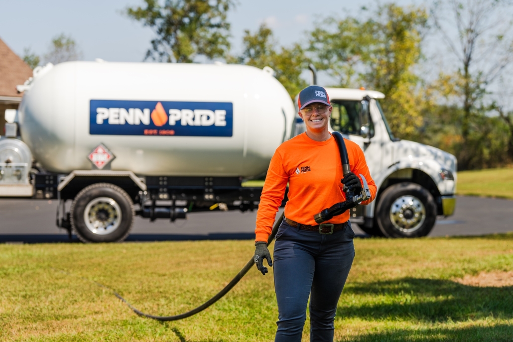 pennpride_actionshots_2025-82 Smiling propane delivery driver walking in front of with hose over shoulder