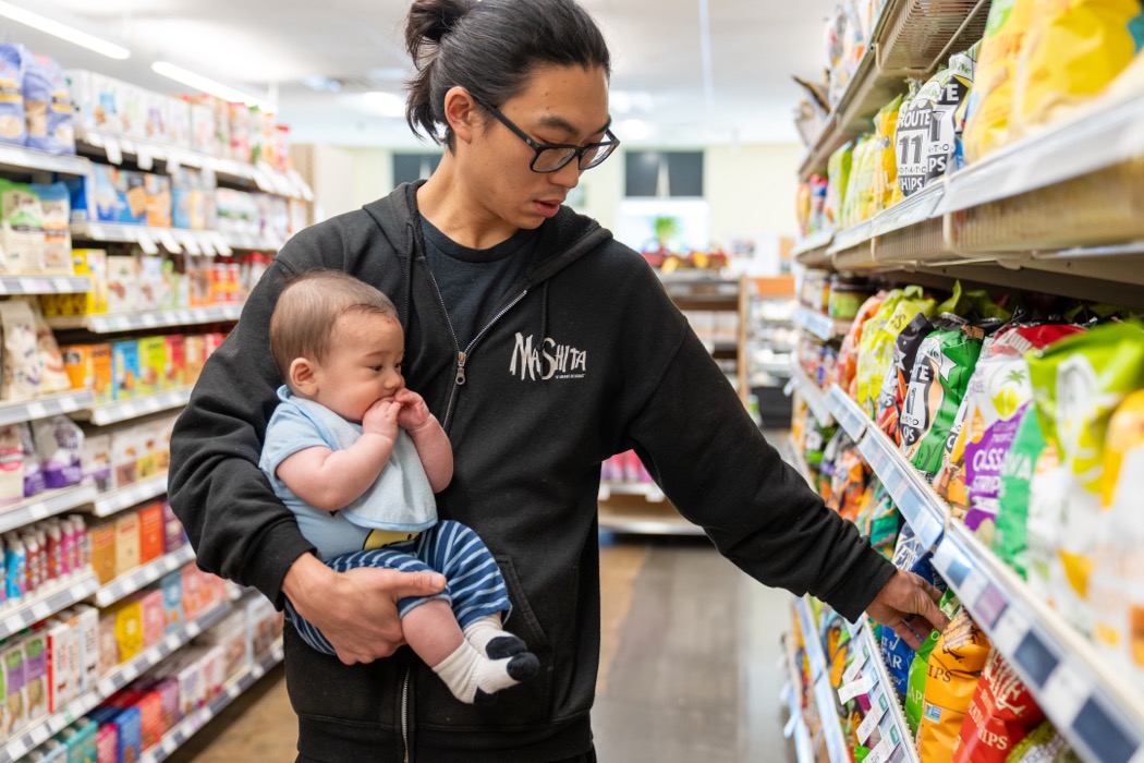 Man holding baby shopping in a grocery aisle at Friendly City Food Co-op in Harrionsburg