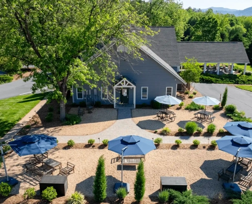 A building with a landscaped outdoor space with blue umbrellas and seating areas.
