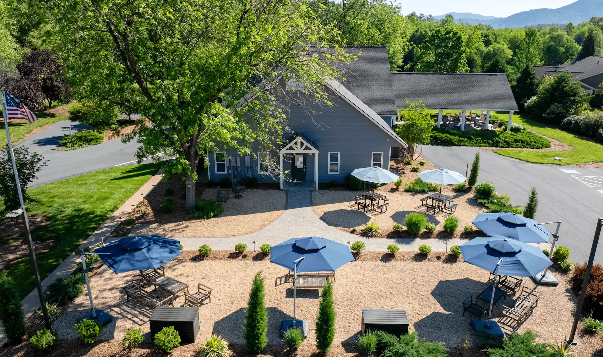 A building with a landscaped outdoor space with blue umbrellas and seating areas.