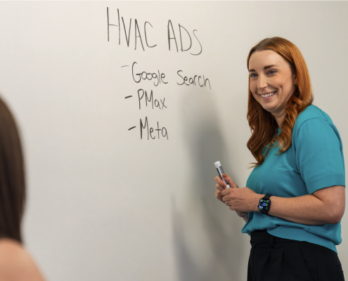 Woman writes on dry erase wall about energy marketing strategies.